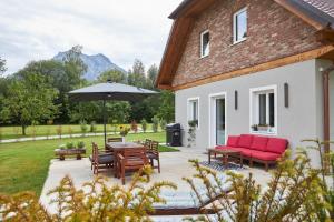 um pátio com uma mesa, cadeiras e um guarda-sol em Seechalet Traunsee em Ort