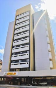 a tall white building with a bus in front of it at Expresso R1 Hotel Economy Suites in Maceió