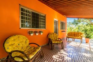 a room with two chairs and an orange wall at Pousada e Restaurante Maria das Flores in Três Marias
