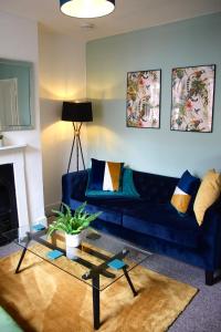 a living room with a blue couch and a glass table at The Velveteen Townhouse in Colchester