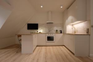 a kitchen with white cabinets and a tv on the wall at Boutique Charme Apartment in Baden-Baden