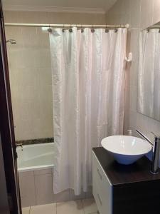 a bathroom with a white shower curtain and a sink at Oasis del Sur in Puerto Madryn +44 photos