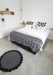 a bedroom with a bed with black and white sheets and a rug at Bellas Cottage in Langebaan