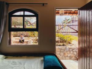 una persona sentada en la ventana de una casa en Chalés Del Rincon en Monte Verde