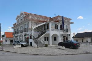 dois carros estacionados em frente a um edifcio em Alojamento Local S. Bartolomeu em Trancoso