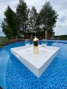 a table with two wine glasses on it next to a swimming pool at Domek na Uboczu in Gryfów Śląski