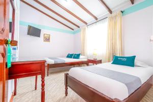 a hotel room with two beds and a television at Hotel Puerta del Sol Popayan in Popayan