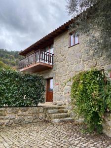 una casa in pietra con balcone sul lato di Gerês Country Stays - Sequeiro a Rio Caldo