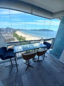 una mesa de cristal y sillas en un balcón con playa en Condomínio de Luxo em Frente à Praia (novinho) en Santos