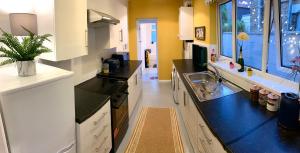 a kitchen with white cabinets and black counter tops at The Velveteen Townhouse in Colchester