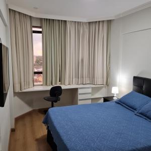 a bedroom with a blue bed and a window at Flat Centro Campinas - L'Hirondelle 125 in Campinas