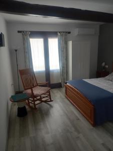 1 dormitorio con cama, silla y ventana en El Mullaero, en Aldeanueva del Camino