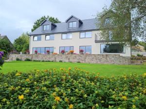 uma grande casa branca com uma parede de pedra e flores em Camden Lodge B&B and Cottage Brecon em Brecon