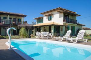 a villa with a swimming pool in front of a house at Pousada Kactus in São João da Barra