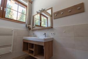 La salle de bains est pourvue d'un lavabo et d'un miroir. dans l'établissement Harrys Alm - Appartements, à Haus im Ennstal