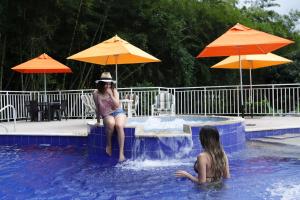 two women are sitting in a swimming pool at Ecohotel Monteverde in La Vega