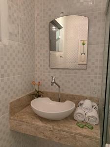 uma casa de banho com lavatório, espelho e toalhas em Sua casa em Angra dos Reis