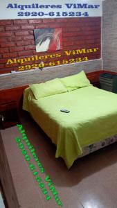 Un dormitorio con una cama con un cartel. en Alquileres Vimar en Las Grutas