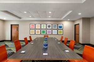 una sala de conferencias con una mesa larga y sillas naranjas en Holiday Inn Express & Suites Pembroke Pines-Sheridan St, an IHG Hotel en Pembroke Pines