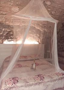 La grotta dell'Antica Calvasino - Jacuzzi في ليتْسّينو: سرير مع مظلة في الغرفة
