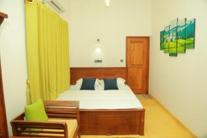 a bedroom with a bed and a chair at Villa Green Heaven Hikkaduwa in Hikkaduwa