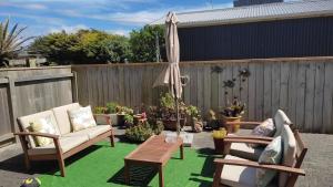 a patio with chairs and a table and an umbrella at Coastal Condo in Waitarere
