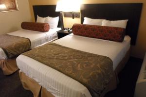 a hotel room with two beds and a lamp at Howard Johnson by Wyndham Las Vegas near the Strip in Las Vegas