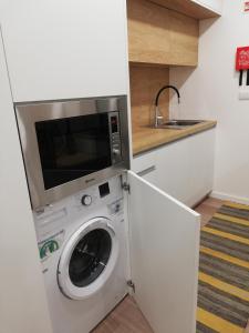 uma máquina de lavar roupa numa cozinha com um micro-ondas em Da' Vila - Alojamento Local em Ponte de Lima