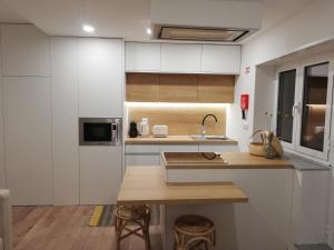 a kitchen with white cabinets and a wooden table at Da' Vila - Alojamento Local in Ponte de Lima