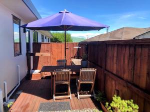 un patio con una mesa y una sombrilla púrpura en Almost Country, en Taupo