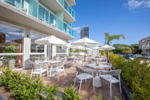 プンタ・デル・エステにあるHotel Soleriosのパティオ(白いテーブル、椅子、パラソル付)