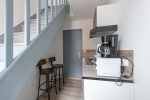 a kitchen with a counter with stools and a staircase at Studianzin in Anzin