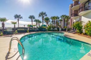 a swimming pool in front of a building with palm trees at Palms Resort in Myrtle Beach