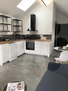eine Küche mit weißen Schränken und schwarzen und weißen Geräten in der Unterkunft L'atelier 1410 in Saint-Amand-les-Eaux