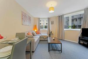 a living room with a couch and a table at Modern & Spacious 2 Bedroom Serviced Apartment Next to Lochend Park - Private Underground Parking & Lift Available - Close to Edinburgh City Centre in Edinburgh
