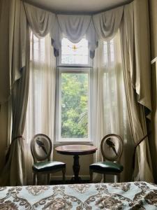 a bedroom with two chairs and a table and a window at Toorak Manor Hotel in Melbourne