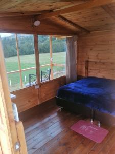 1 dormitorio en una cabaña de madera con cama y ventana en Cabañas el mirador del tomine en Guatavita