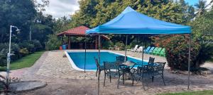a table and chairs under a blue umbrella next to a pool at Hacienda De La Bahia in Arroyo Barril