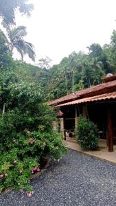a building with a bush with flowers in front of it at Canto do Sabiá PETAR Hospedagem in Iporanga