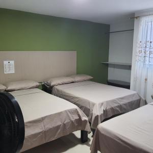 three beds in a room with green walls at Hotel Velices in Buga