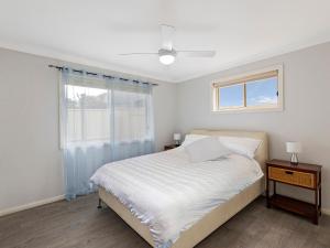 a white bedroom with a bed and a window at Bonnieview House in Shelly Beach