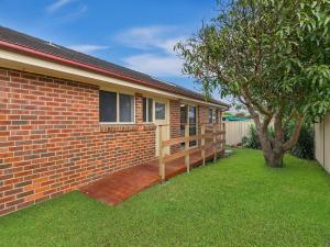 a brick house with a porch and a tree at Bonnieview House in Shelly Beach