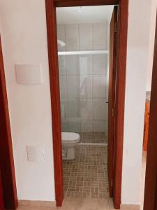 a bathroom with a toilet and a door open at Pousada Dunas Da Joaquina Novo in Florianópolis