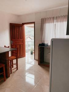 a kitchen with a refrigerator and a table in it at Pousada Dunas Da Joaquina Novo in Florianópolis