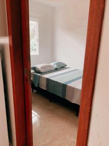 um pequeno quarto com uma cama num quarto em Pousada Dunas Da Joaquina Novo em Florianópolis