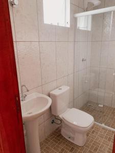 a white bathroom with a toilet and a sink at Pousada Dunas Da Joaquina Novo in Florianópolis