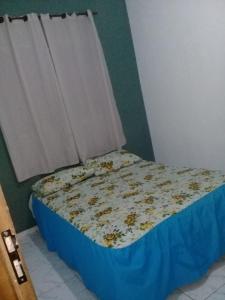 a small bed in a room with a blue sheet and a window at Casa pé na areia in Ubatuba