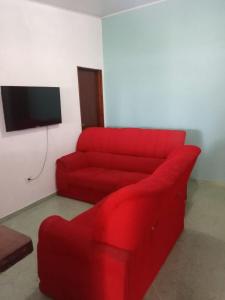 a red couch in a living room with a tv at Casa pé na areia in Ubatuba