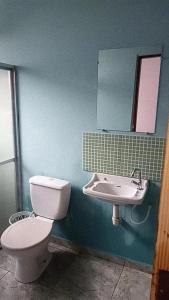 a bathroom with a toilet and a sink and a mirror at Casa pé na areia in Ubatuba