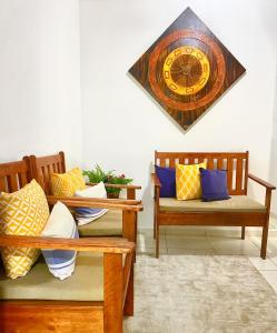 a clock hanging on a wall above two benches at Cobertura Duplex: piscina, três quartos e beira á mar in Ilhéus
